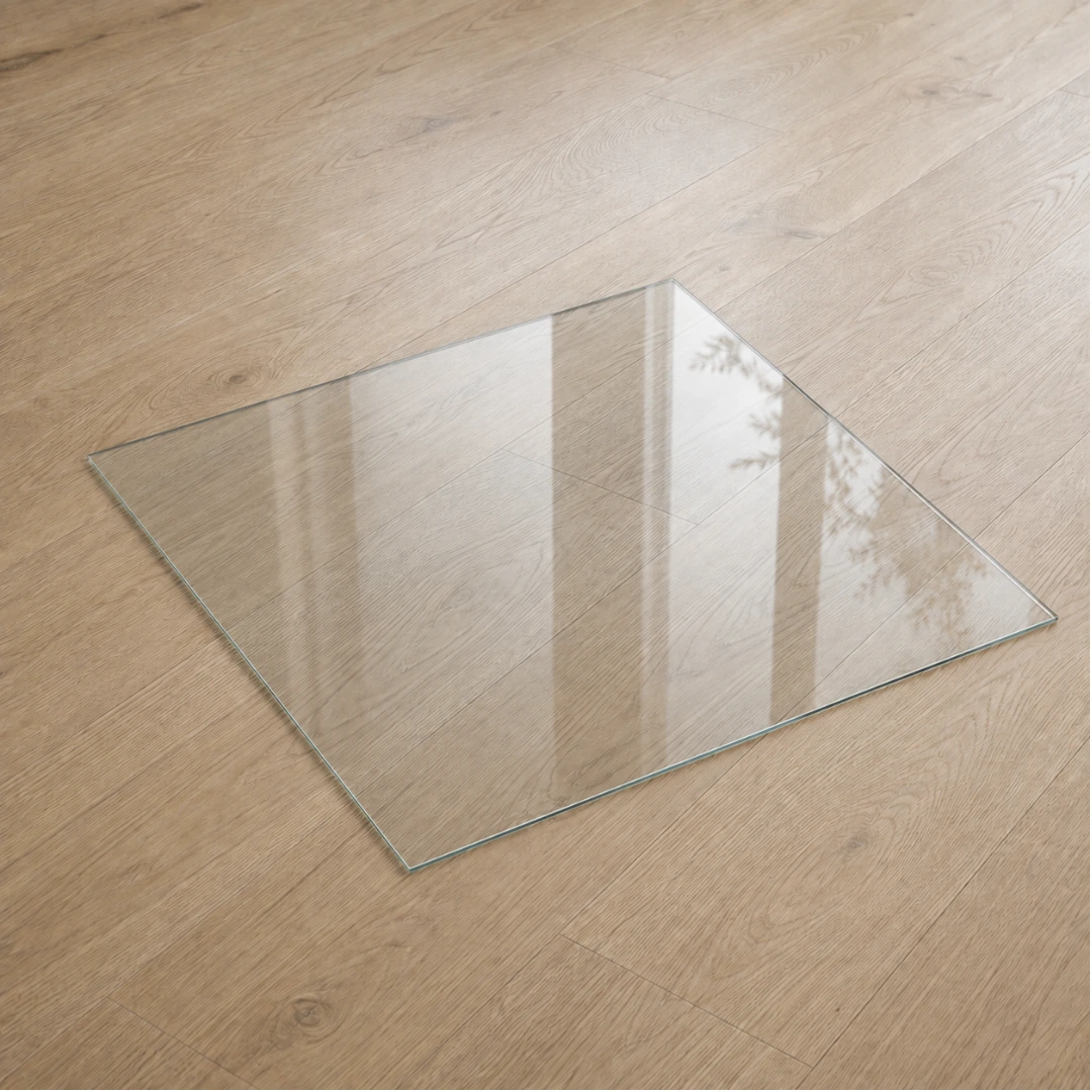 Funkenschutzplatte aus Klarglas in quadratischer Form, transparente Glasplatte als Bodenschutz vor dem Kamin auf hellem Holzboden
